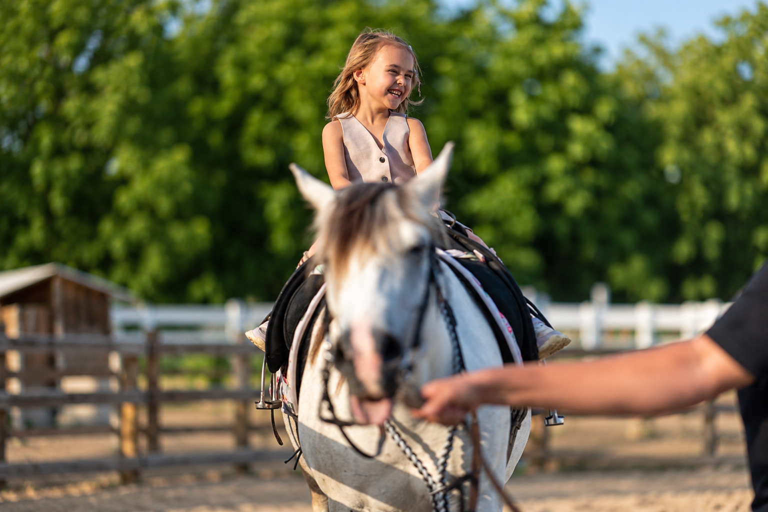 Copil călare la Gallop, însoțit de un adult.